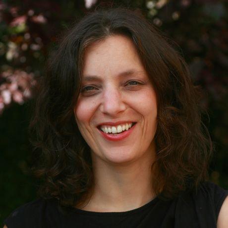A woman with shoulder length brown hair, wearing a black dress