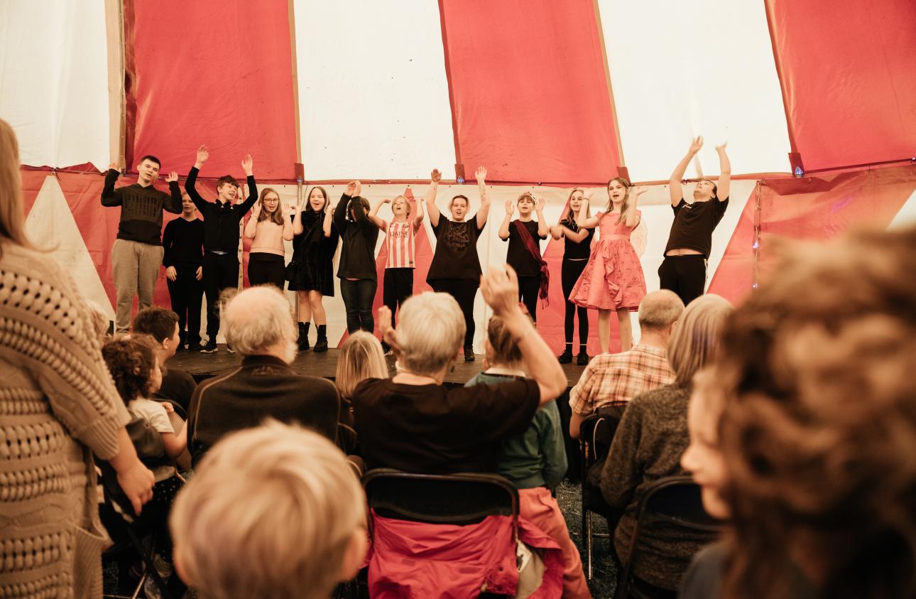 the whole our stories ensemble on stage performing the 'Moose Song' at tapton lock festival