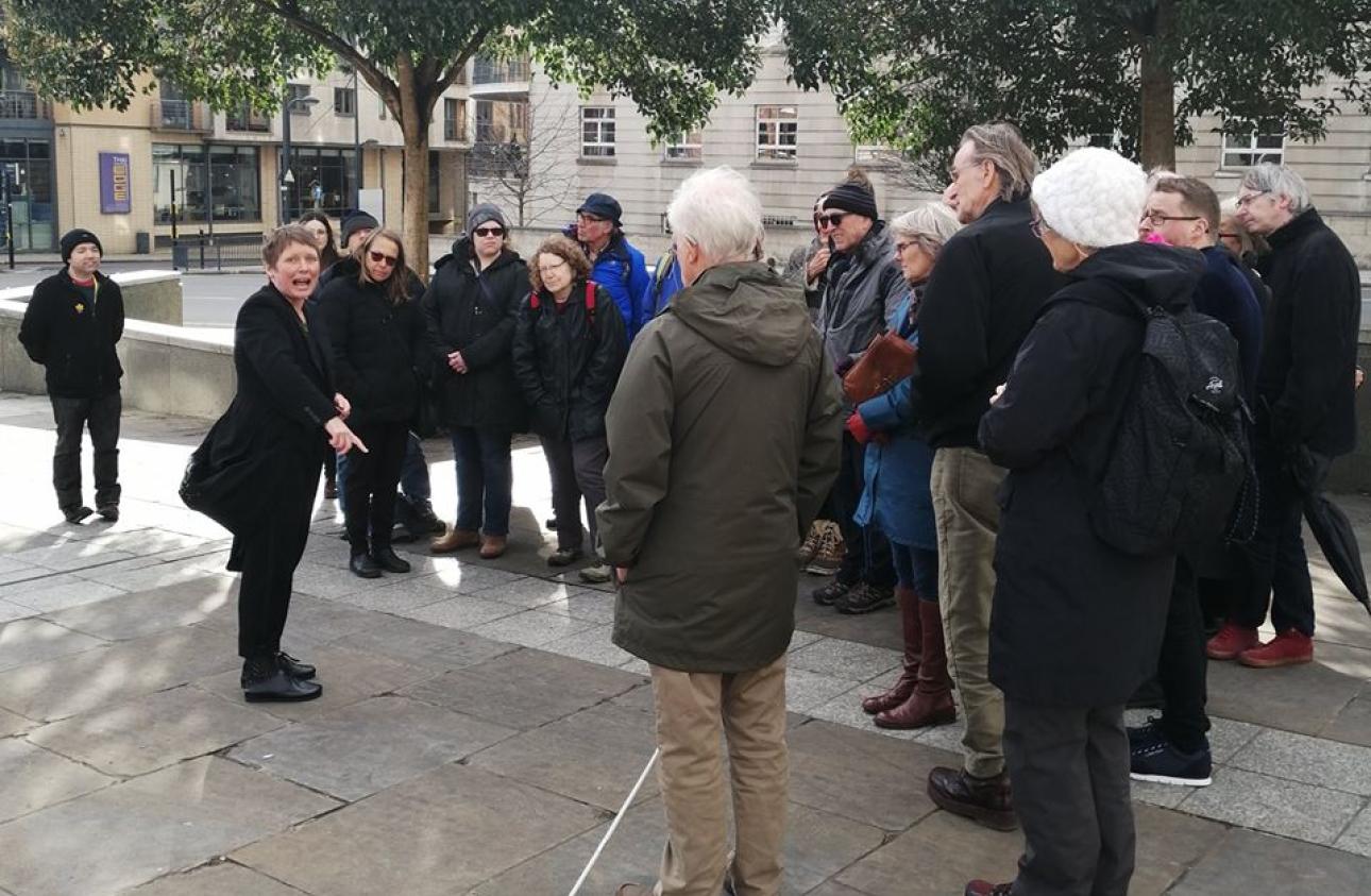 Ursula Holden Gill leads a story walk in Leeds Millennium Square with a crowd of people