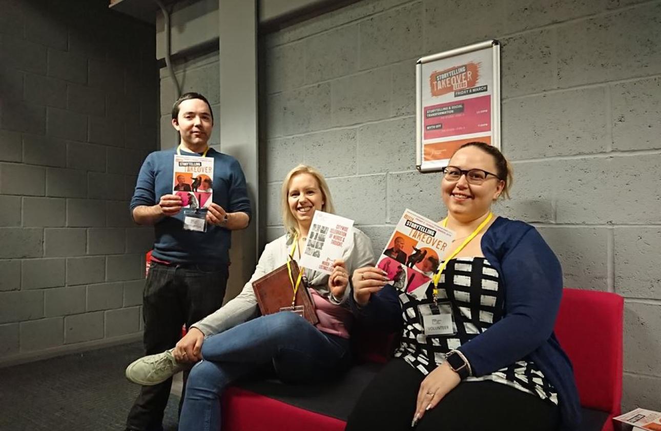 Three people sitting on a red sofa holding Takeover leaflets