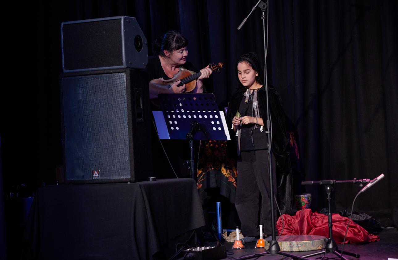 Musician Anna is playing the violin while one of the young participants sings alongside her. 