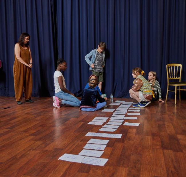 A group of young people are on the floor mapping on paper a story.