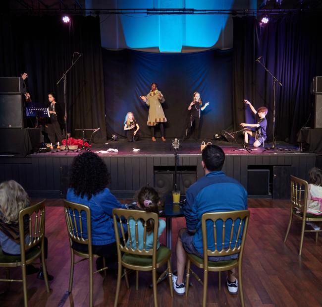 A photograph of a group of performers on stage.