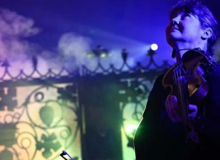 Ann Jones is playing a violin and looking at the sky